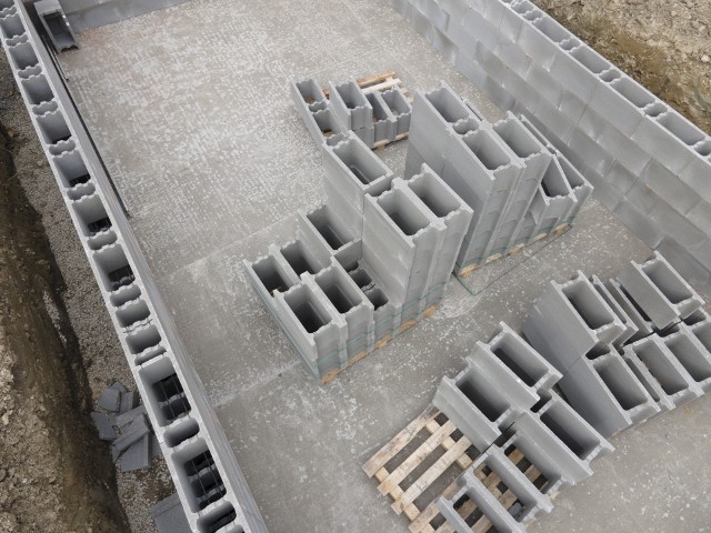 Aerial drone photo of a construction site for a pool, concrete blocks already coated and bricked up with construction adhesive