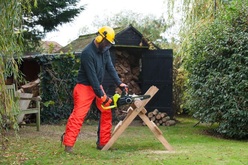 Mężczyzna używa akumulatorowej pilarki RYOBI do cięcia drewna