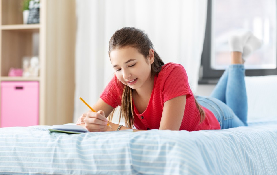 Nastolatka na łóżku pisze pamiętnik