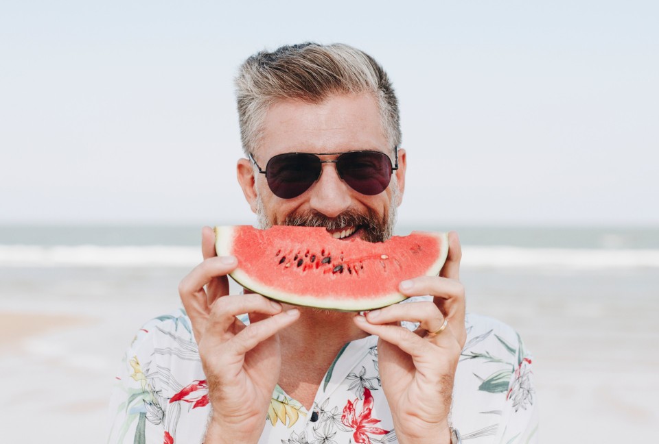 Mature man eating watermelon at the beach