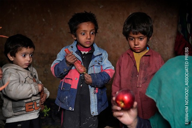 Afgańskie dzieci z przedmieść Kabulu wpatrują się w jabłko, które ich matka wyżebrała na ulicach miasta. 2 lutego 2023