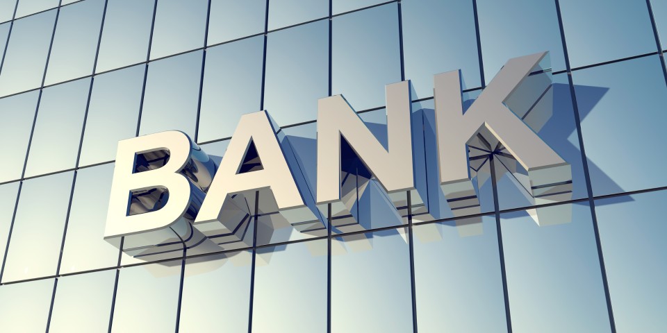 Glass front of a bank building with the word "BANK" on the...