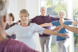 Seniors following teacher in yoga exercise class.