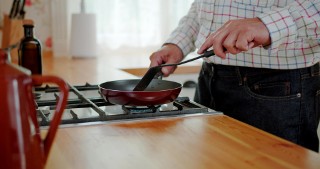 Hands of a man who is cooking with a frying pan